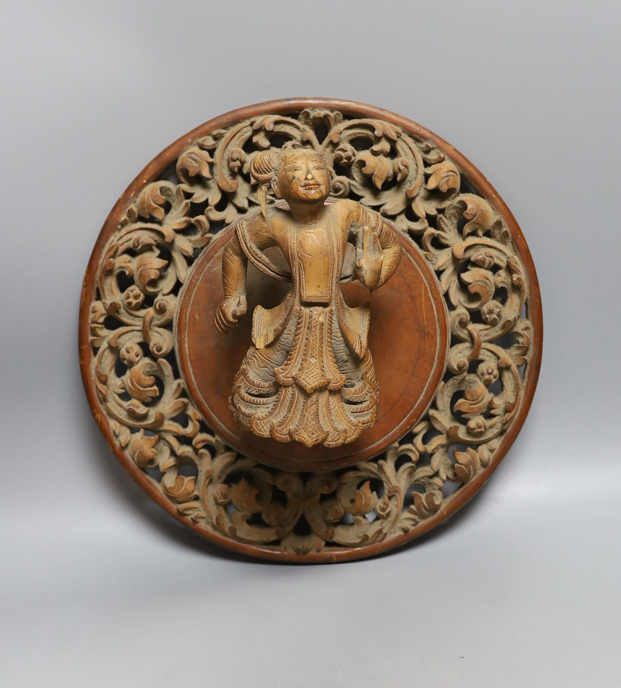 A Chinese blue and white plate with floral decoration, 23cm diameter, together with another plate and wooden panel relief of oriental figure (3)